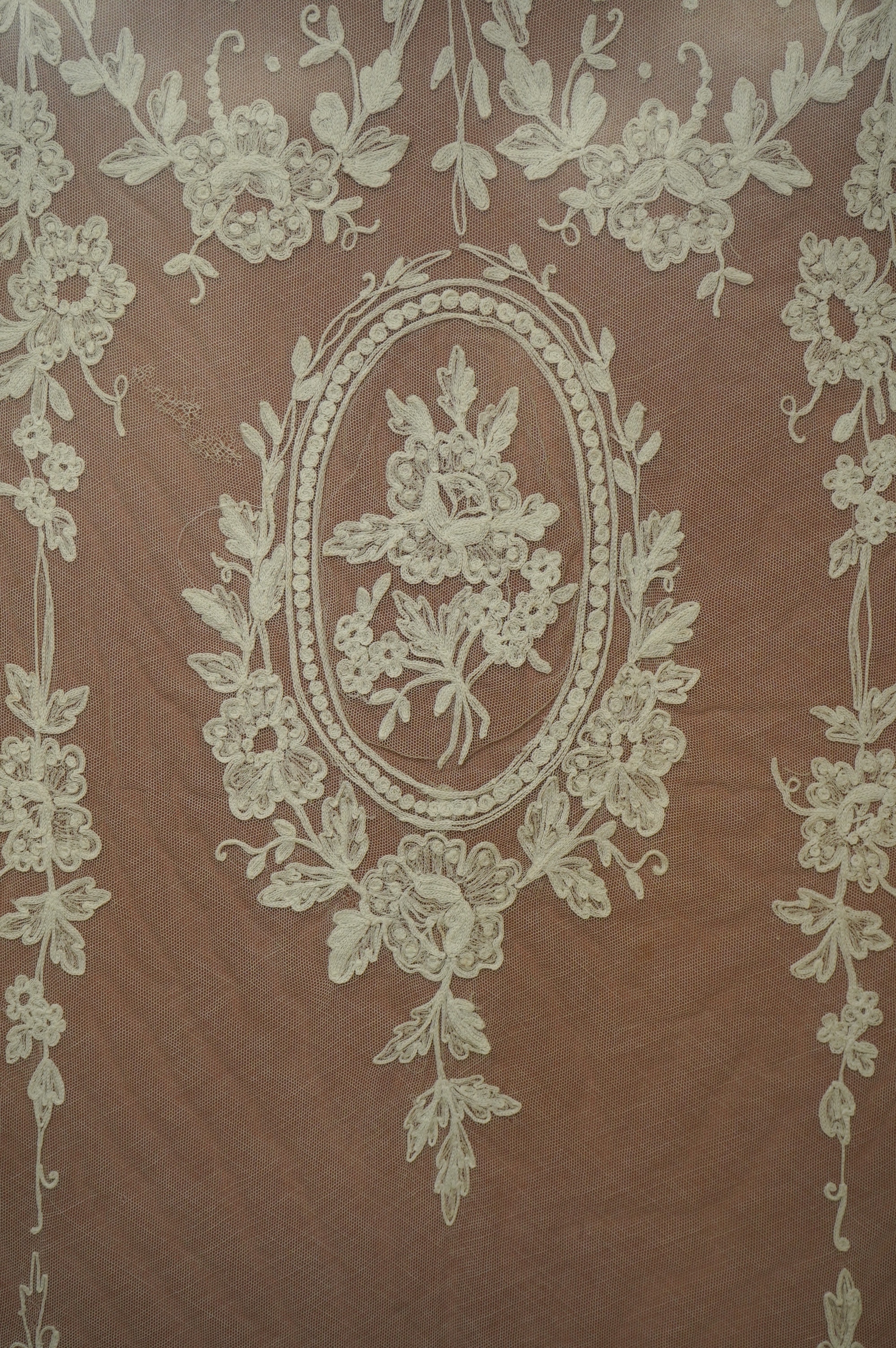 A framed Victorian white work needlerun lace stole with decorative urns and flowers each end, 154cm long x 33cm wide. Condition - has small darns to net one end, otherwise good.